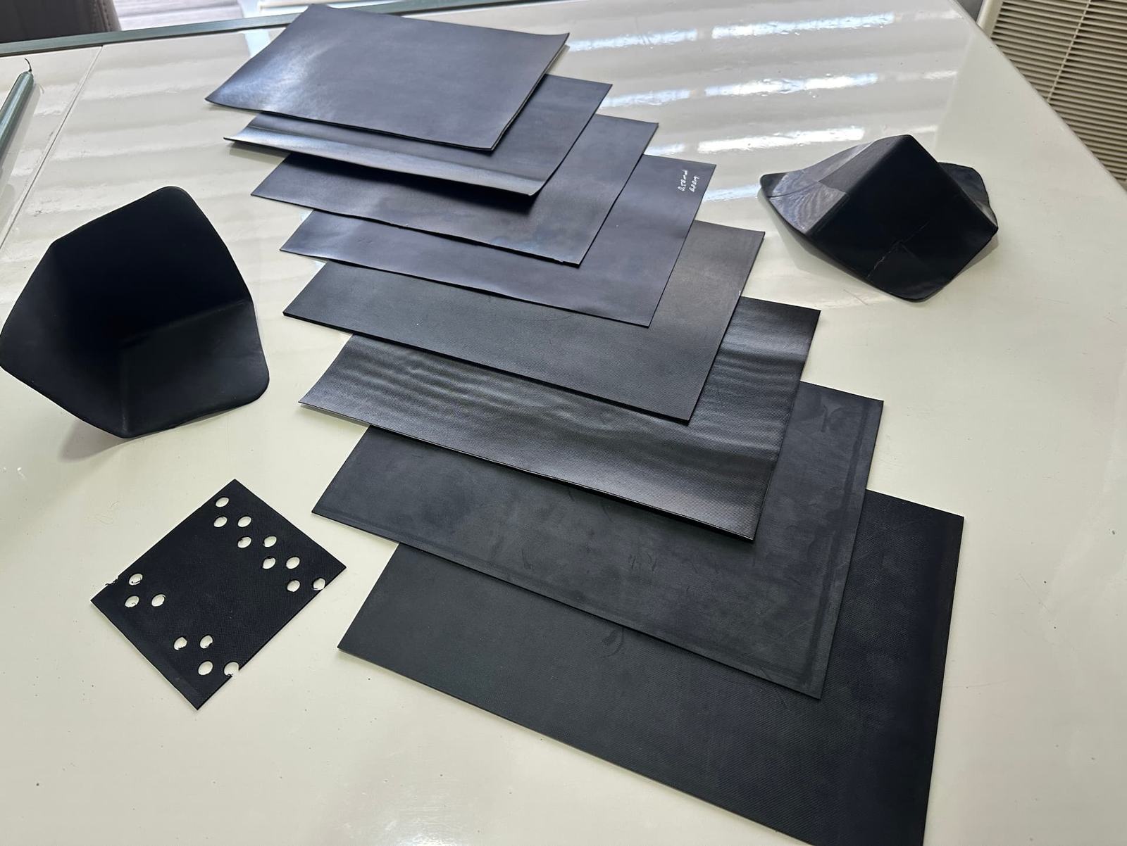 Range of EPDM sheet gauges and preformed corner pieces laid out on a table