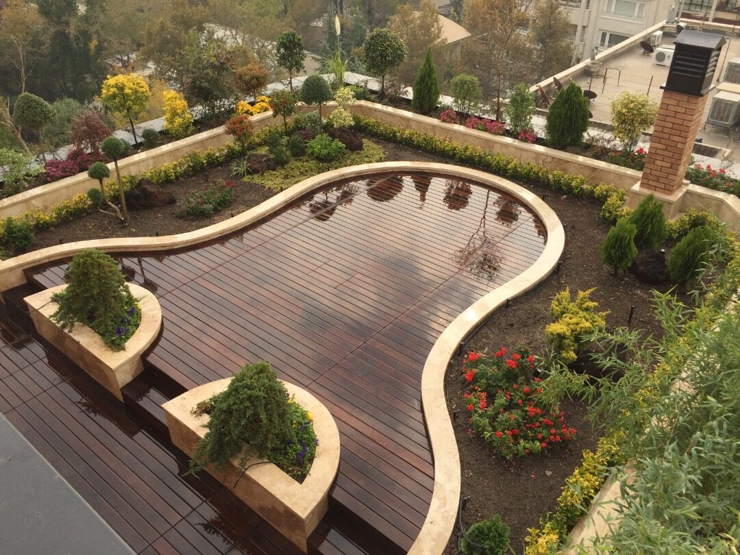 A completed Green Area garden terrace with curved hardwood decking, stone copings and layered planting