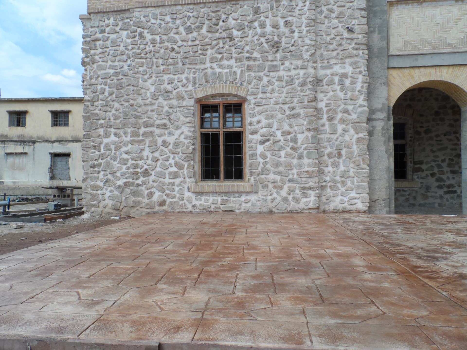 Stamped concrete courtyard paving laid against a handbuilt natural stone façade